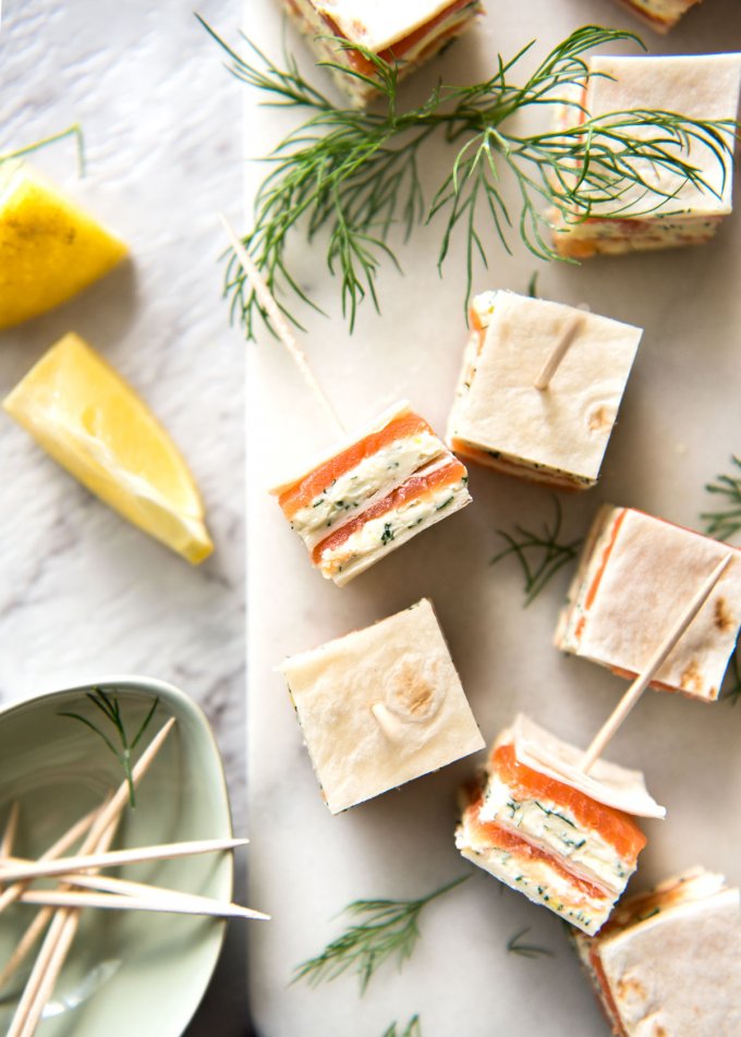 smoked salmon appetizers with dill and toothpicks on cutting board