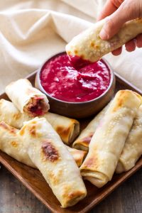 turkey cranberry brie egg rolls on a plate with dipping sauce