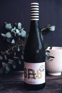 wine bottle in front of eucalyptus leaves