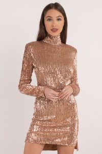 Don't miss out on our Sandstorm Mock Neck Bodycon Dress. Featuring metallic fabrication, long sleeves, and mock neck detail on a bodycon dress. Pair with your favorite heels.
