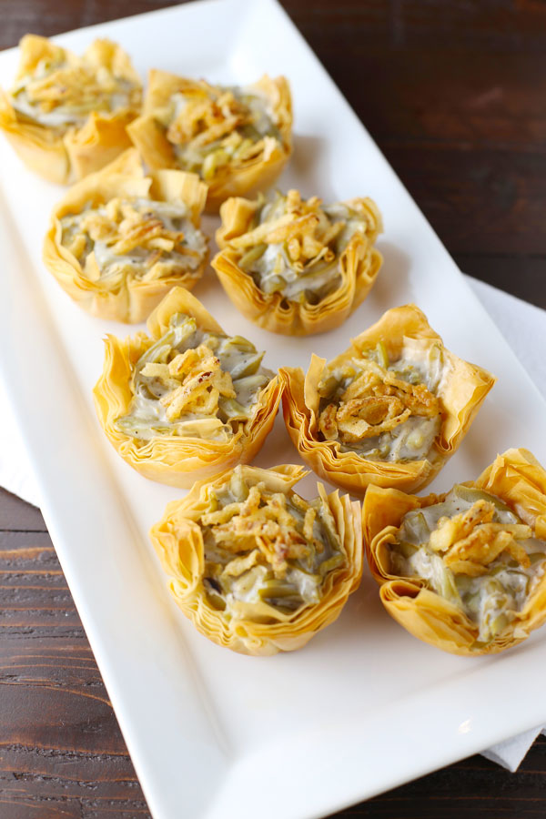 small pastries on a rectangle plate topped with green bean casserole and fried onions