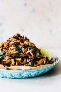 easy slow cooker recipes plate of shredded carnitas in a blue plate with tortillas and lime
