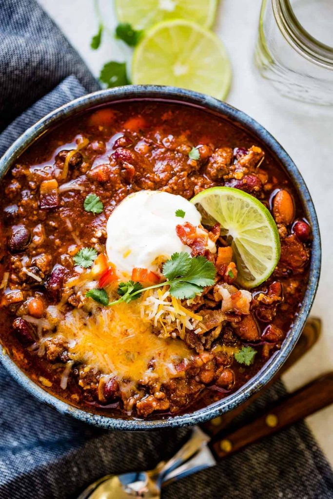 bowl of hearty chili with sour cream and lime