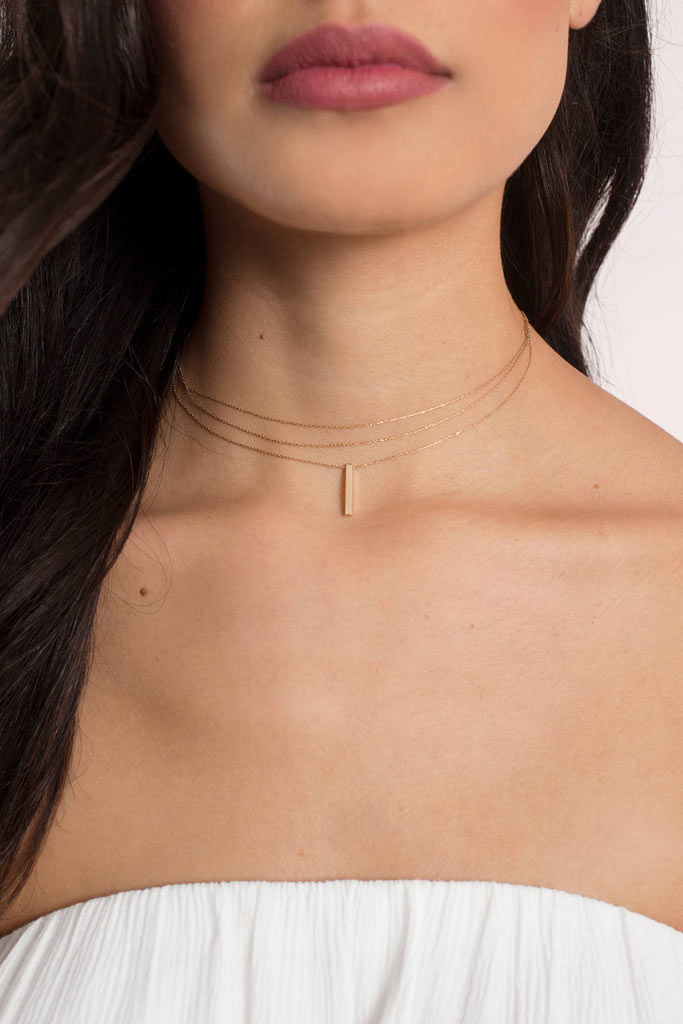 A simple gold necklace with a bar pendant